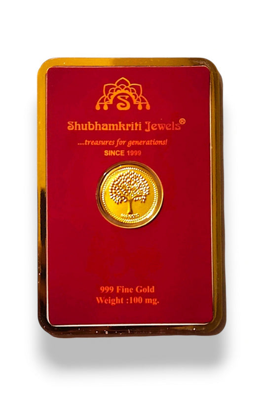 A 100 mg fine gold coin featuring a tree of life design, presented on a red backing card with gold trim. The brand 'Shubhamkriti Jewels' is clearly printed on the card.